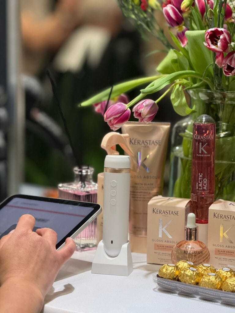 Stanowisko diagnostyczne podczas Dni Kérastase w salonie Agneess – tablet, kamera K-Scan i kosmetyki z linii Kérastase Gloss Absolu na tle bukietu tulipanów