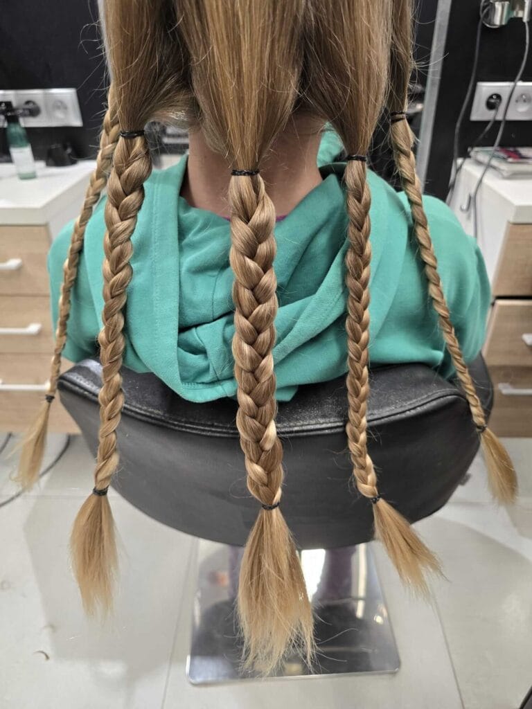 Włosy podzielone na warkocze przed ścięciem w ramach akcji Podziel Się Dzieciństwem