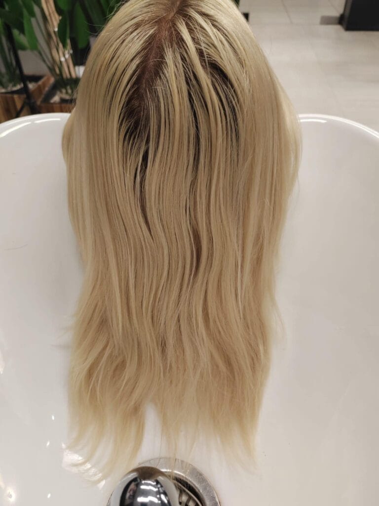 Włosy klientki przed zabiegiem – widoczny odrost i ciepły blond z nierówną tonacją.