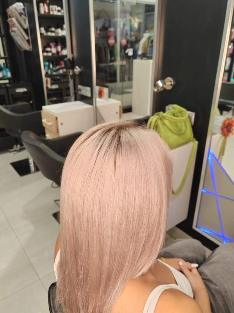 Włosy po koloryzacji w salonie Agneess, widziane w ciepłym świetle – pastelowy, różowawy blond z beżowym tonem.