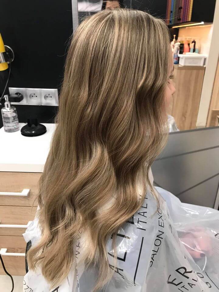 Długie, falowane włosy z naturalnym balayage w odcieniach beżowego i miodowego blondu. Koloryzacja Agneess, Ursynów.