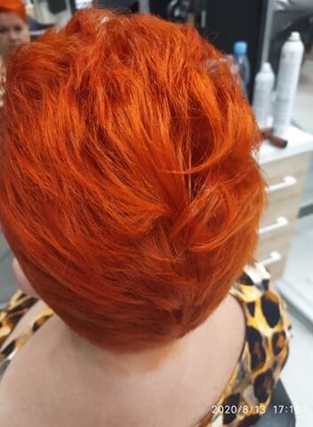 Krótka fryzura w intensywnym, płomiennym, jaskrawo-pomarańczowym kolorze. Koloryzacja odważna, praca Salonu Agneess.