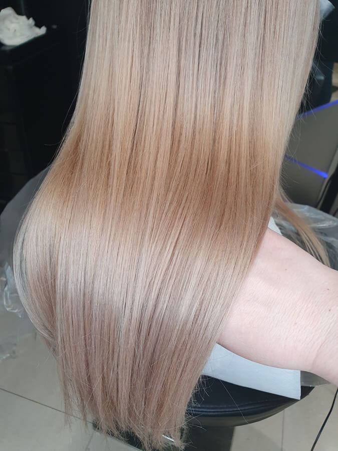 Jednolita koloryzacja blond w ciepłej, miodowej tonacji na prostych, długich włosach. Intensywny połysk. Praca Salonu Agneess.