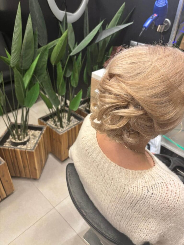 Niskie upięcie z podwiniętych pasm blond – fryzura na specjalną okazję